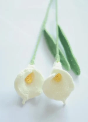 Crocheted white calla lilies with green leaves.