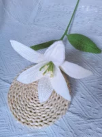 Crocheted white lily with green leaves.
