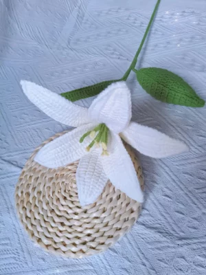 Crocheted white lily with green leaves.