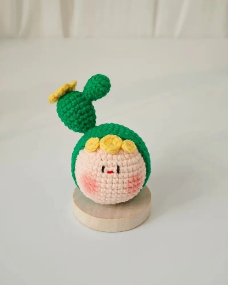 Crocheted cactus-themed doll, light pink cheeks, yellow flower crown.