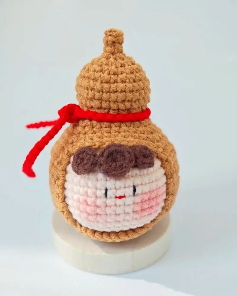 Cute crocheted gourd figurine,  red scarf,  kawaii face.