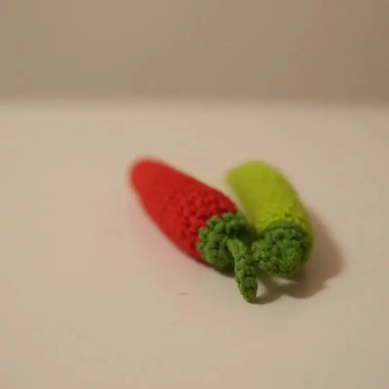 Two crocheted chili peppers, red and green.