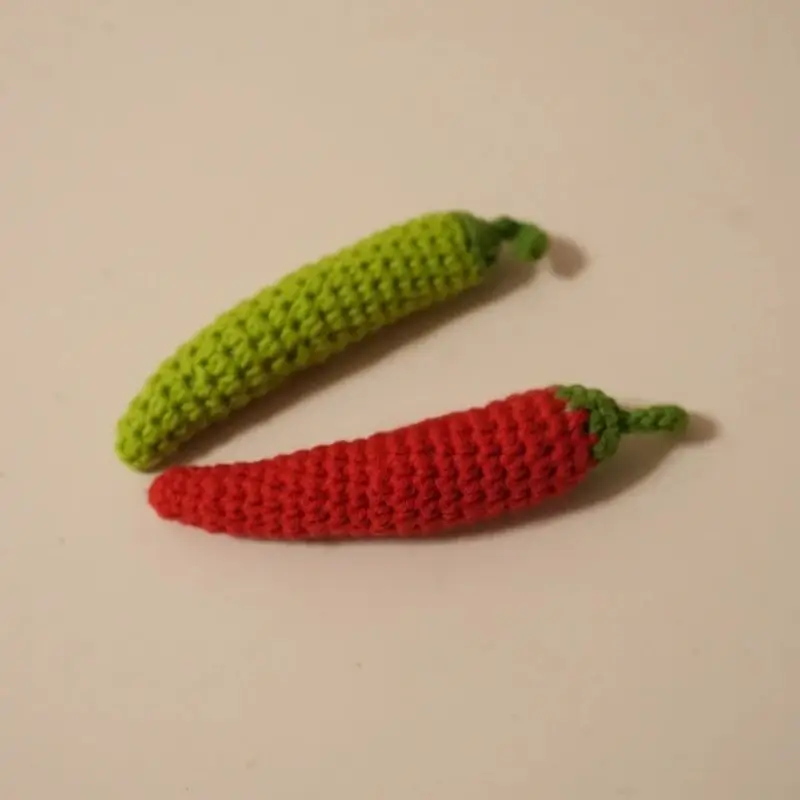 Two crocheted chili peppers, green and red.