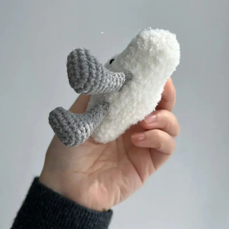 Crochet fluffy white toy, gray legs.