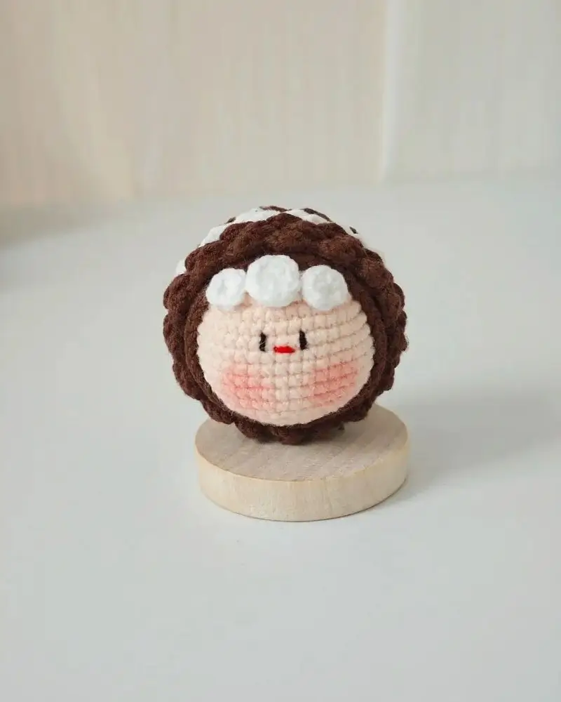 Crocheted amigurumi character, brown hair, white accents.