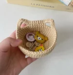 Small crocheted beige basket with bear charms and buttons.
