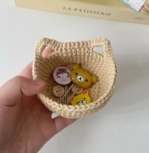 Small crocheted beige basket with bear charms and buttons.