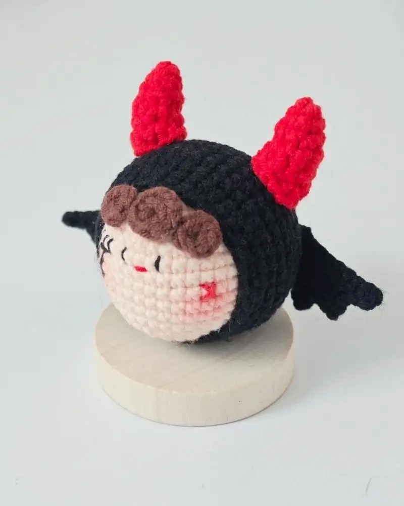 Crocheted devil doll, red horns, black costume.