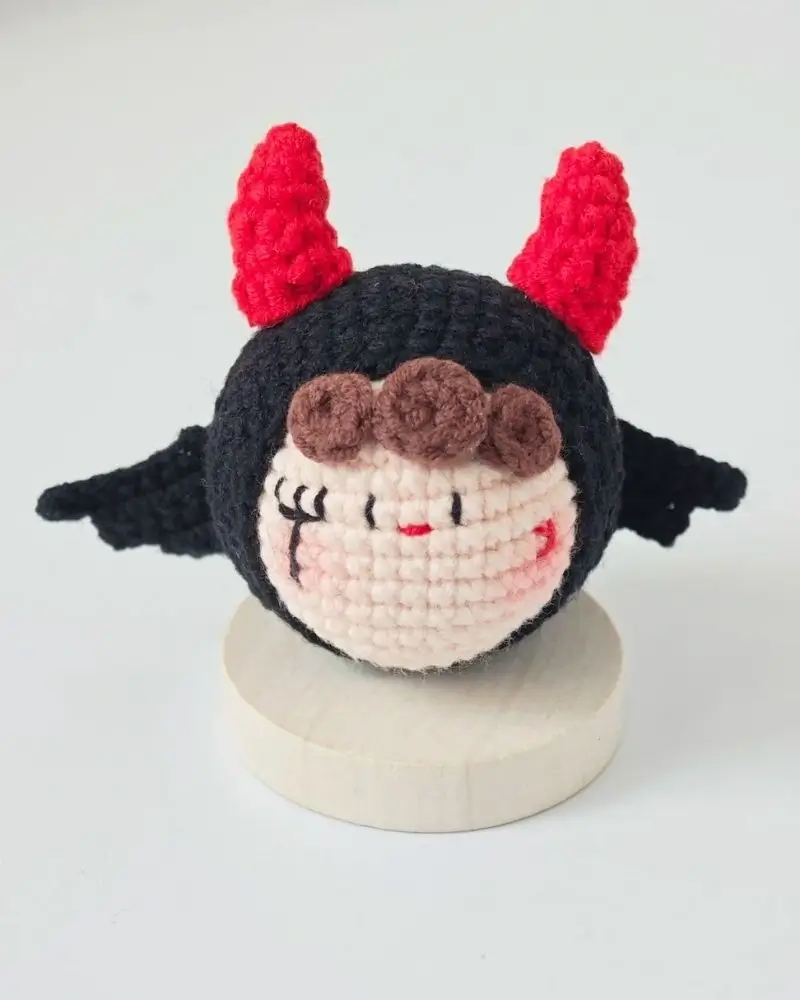 Crocheted devil doll with red horns.