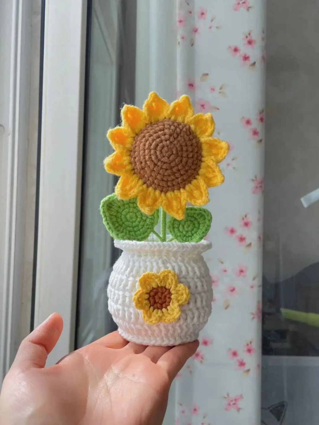 Crocheted sunflower in a small white pot.