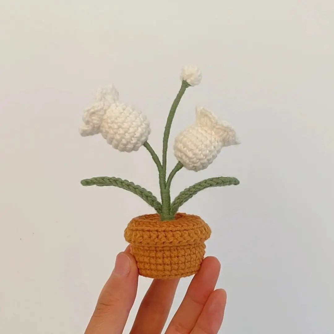 Crocheted white flower in terracotta pot.