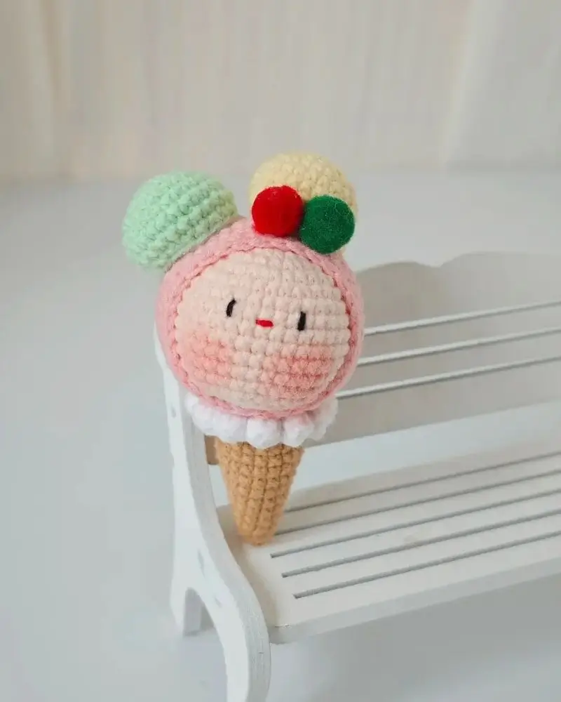 Crocheted ice cream cone toy, pink ombre swirl, colorful sprinkles.