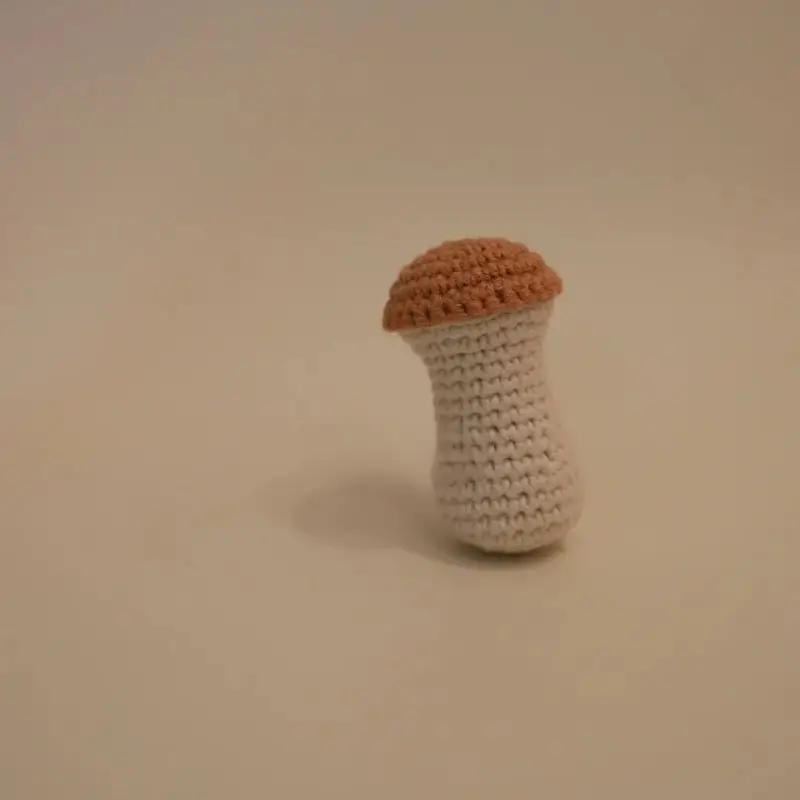 Crocheted mushroom toy, light beige/cream body, terracotta cap.