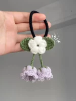 Crochet hair tie with white flower and two purple flowers.