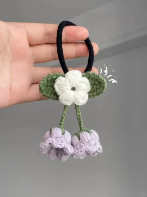 Crochet hair tie with white flower and two purple flowers.
