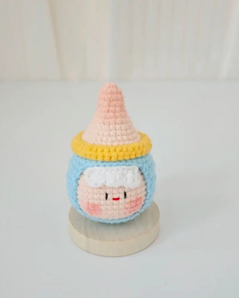 Cute crocheted character, light blue, pink, and yellow.