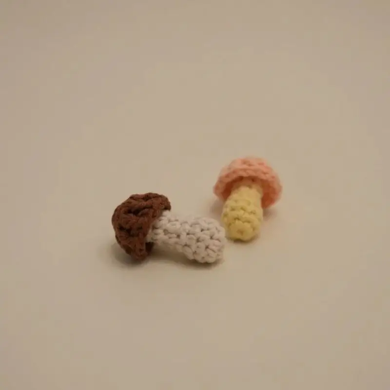 Two crocheted mushrooms, one brown, one light pink/peach.