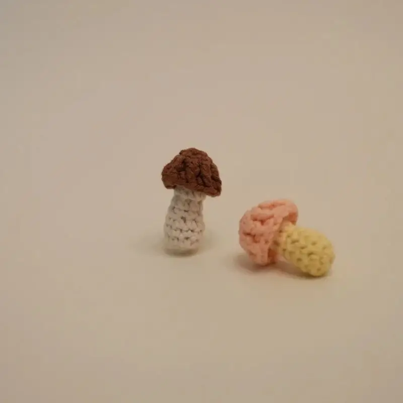 Two crocheted mushrooms, one brown, one pink.