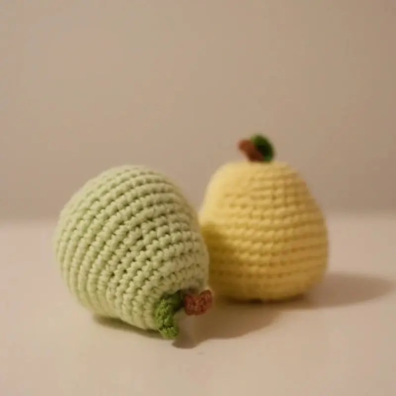 Two crocheted pears, one light green, one yellow.