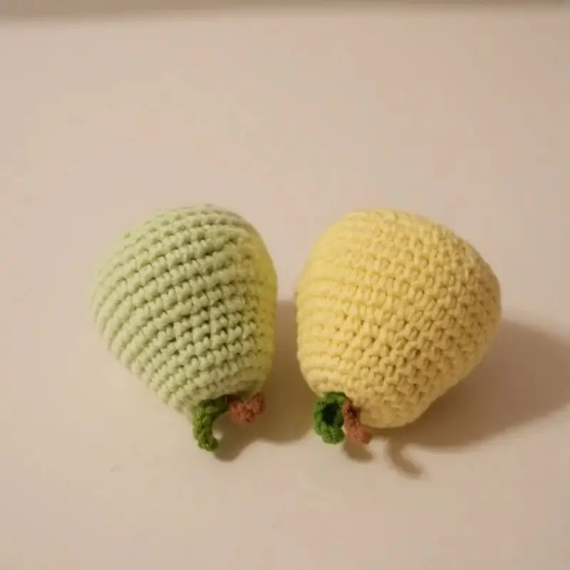 Two crocheted pear-shaped toys, light green and light yellow.