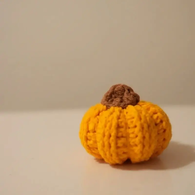 Small crocheted pumpkin, orange/yellow,  brown stem.