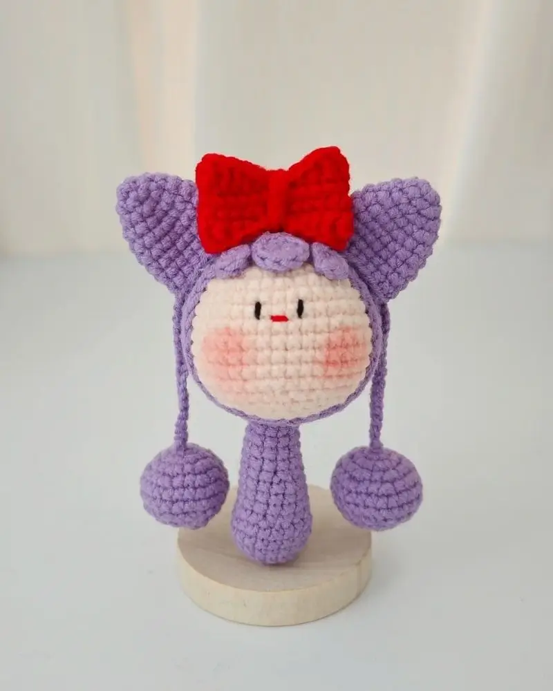 Crocheted purple doll with red bow,  cute baby toy.