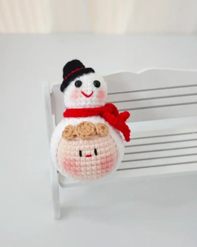 Crocheted snowman, white, red scarf, black hat.