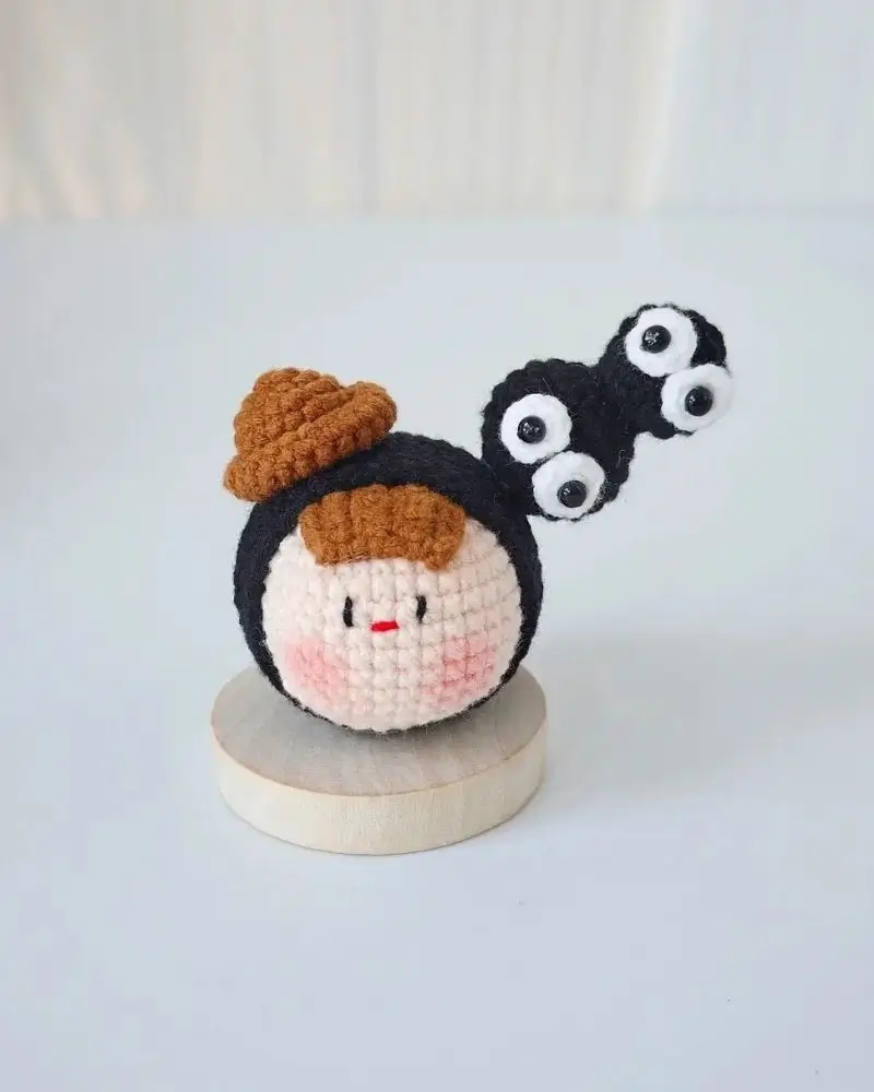Crocheted character, brown hat, big eyes.