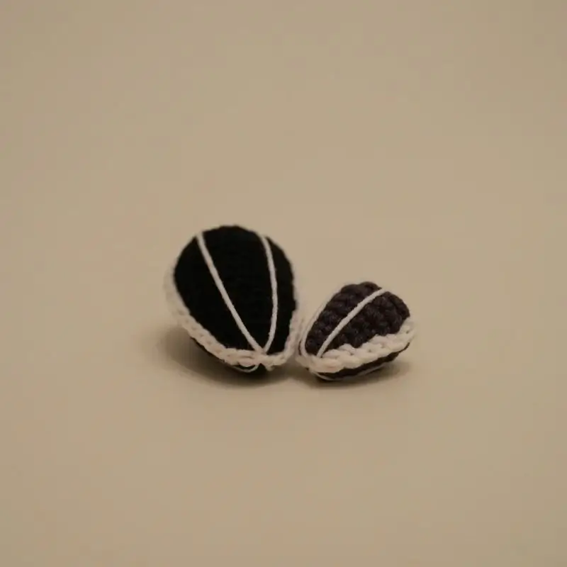 Two crocheted sunflower seeds, dark and light brown,  small.