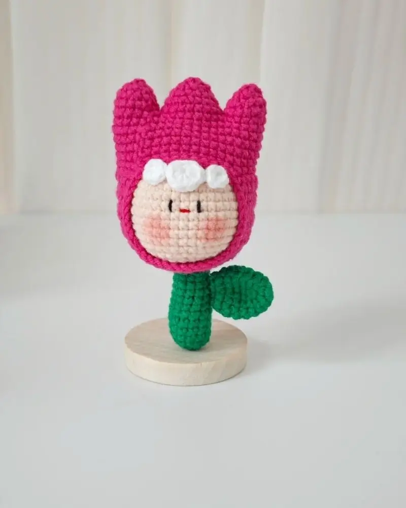 Pink crocheted tulip flower, cute face, green leaf.