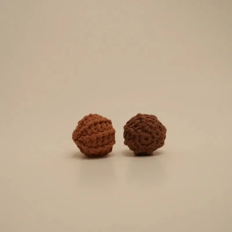 Two crocheted, textured balls, light and dark brown.