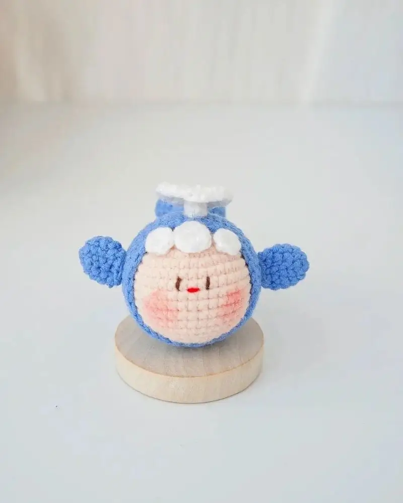 Crocheted blue airplane-shaped toy, cute face.