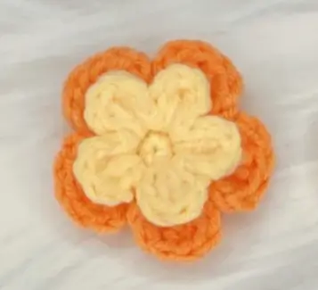 Crocheted orange and cream flower, craft project.