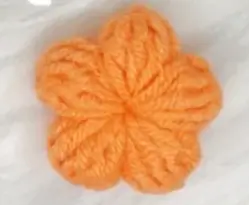 Orange knitted flower, craft embellishment.