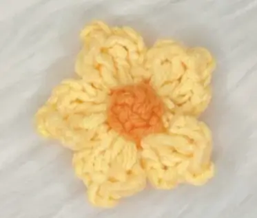 Crocheted yellow flower, orange center.  Handmade craft.