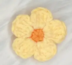 Crochet flower, light yellow, orange center.