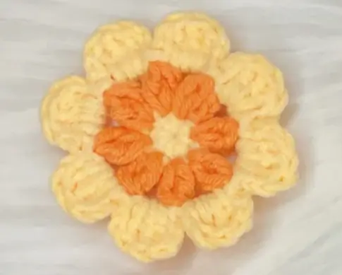 Crocheted flower, orange and pale yellow.