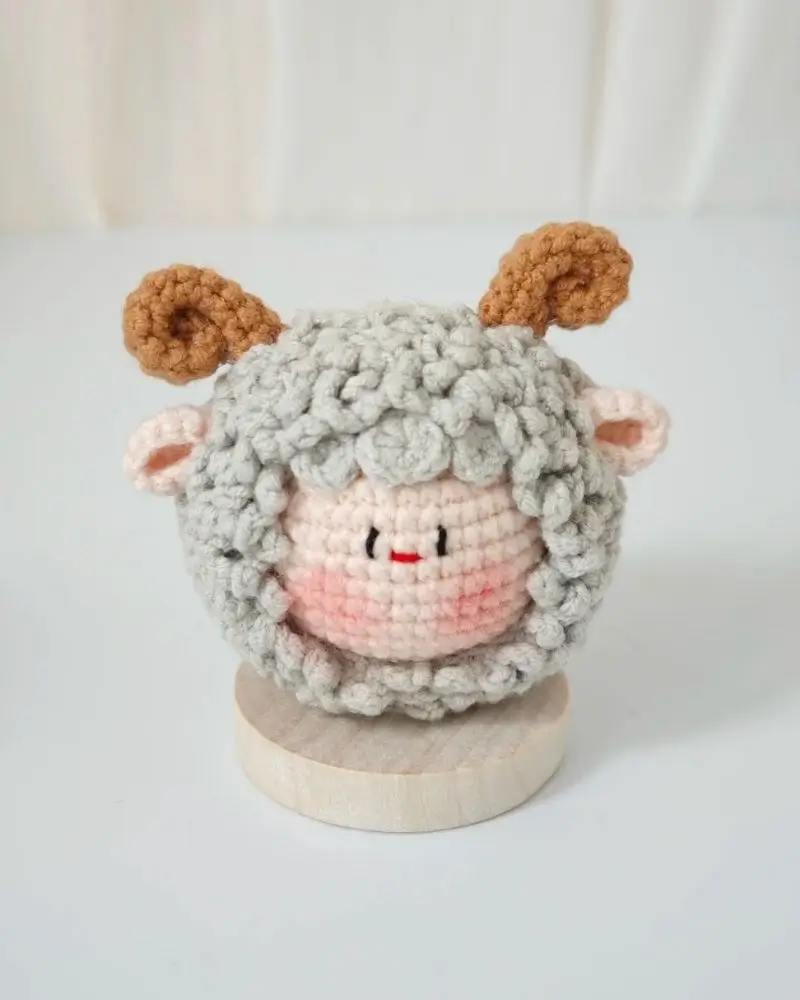 Cute crocheted sheep figurine on wooden base.