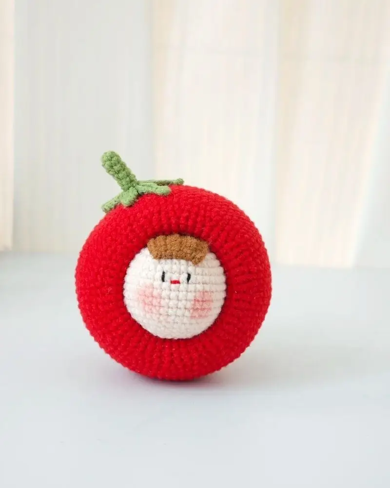 Crocheted red tomato with a face.  Cute amigurumi.