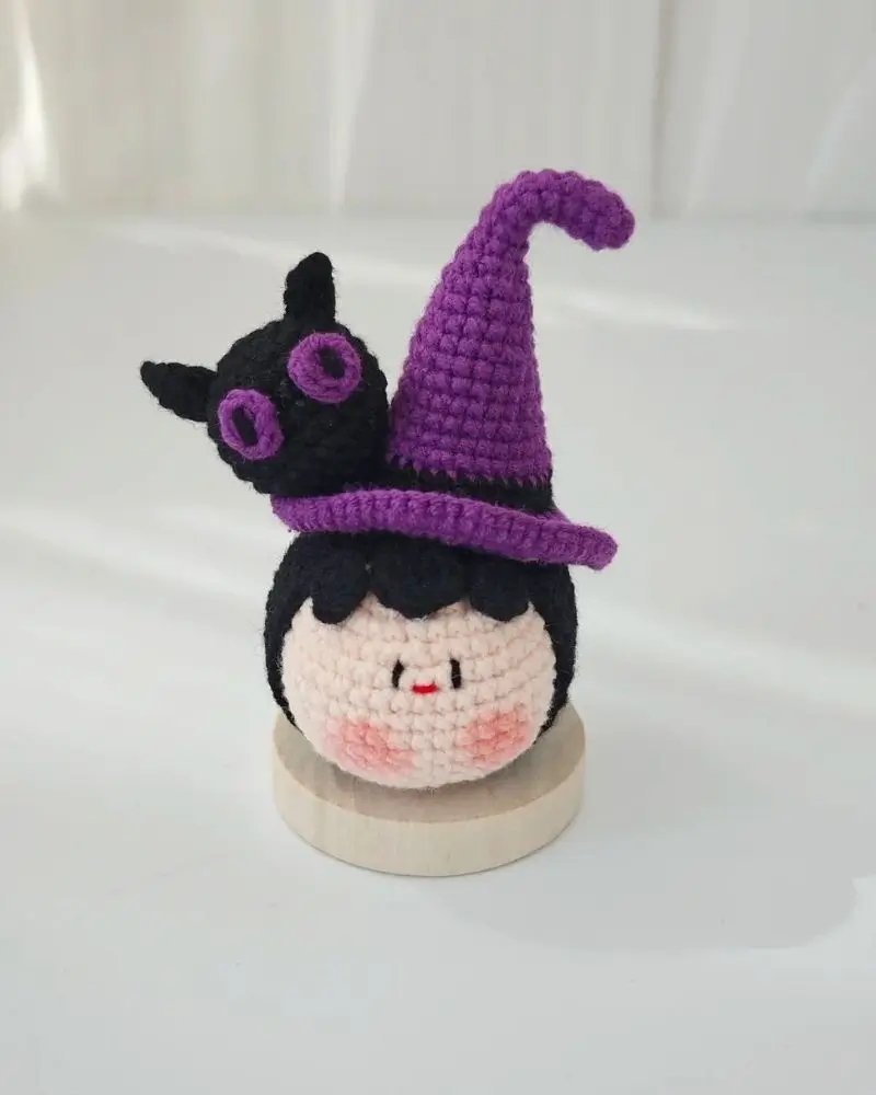 Crocheted witch doll, purple hat, black cat.
