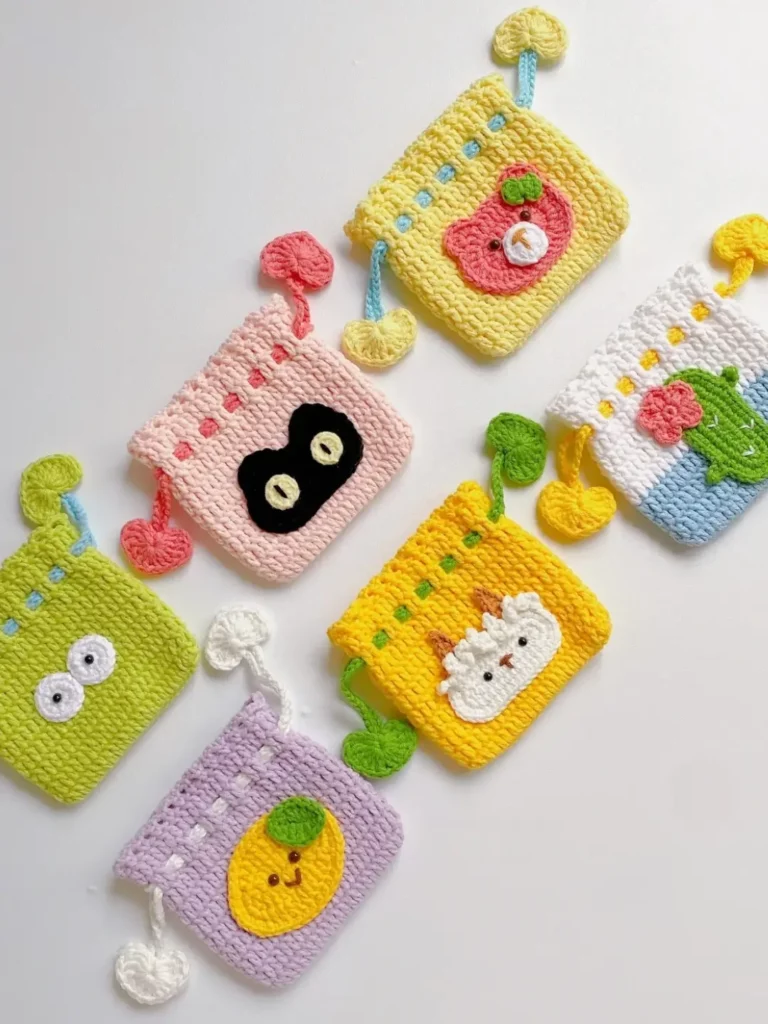Colorful crocheted pouches with animal and fruit designs.