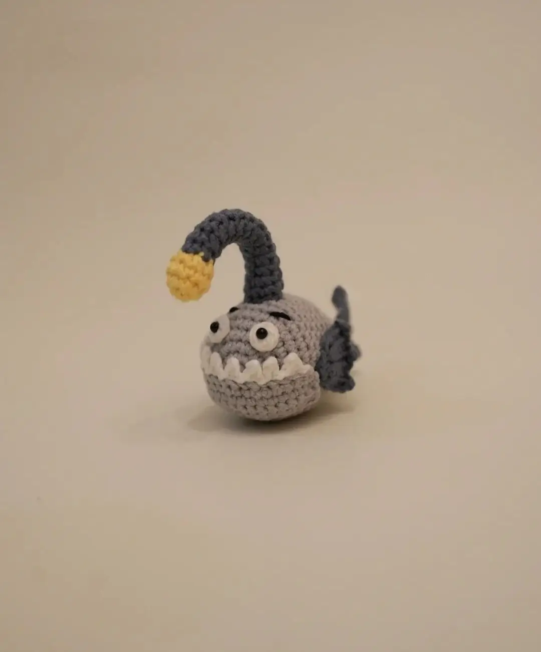 Crocheted anglerfish toy, gray and blue.