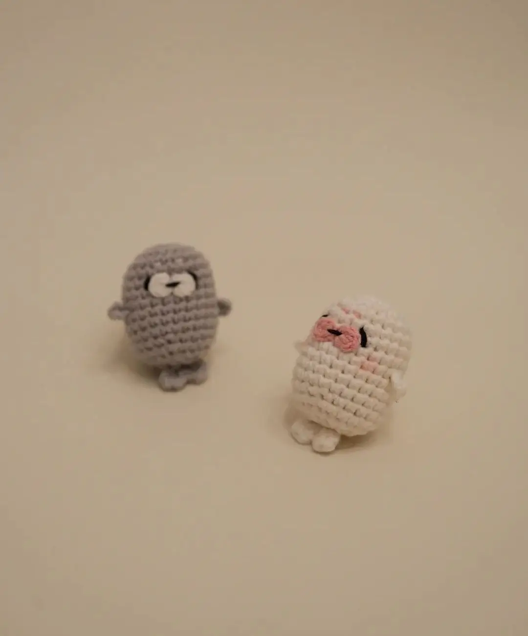 Two crocheted sea lion toys, grey and white.