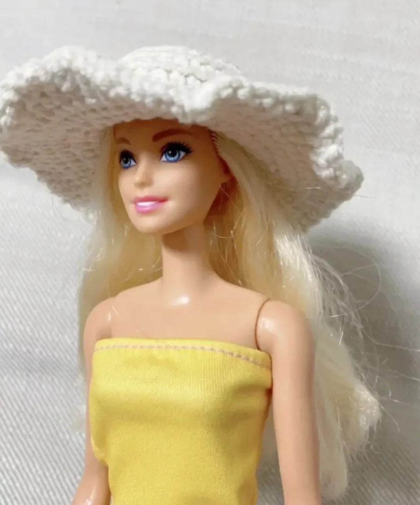 Barbie doll with white crochet sun hat and yellow top.