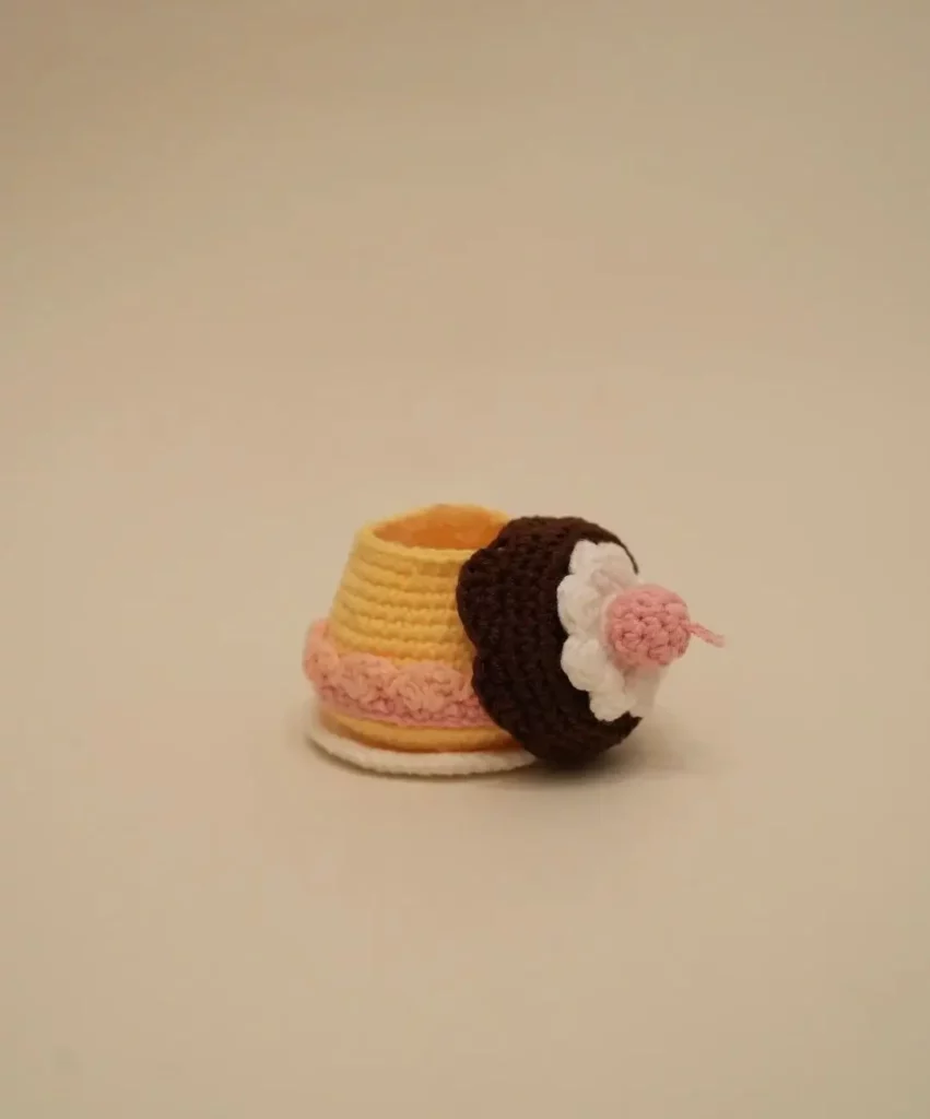 Crocheted cupcake, yellow, brown, pink.