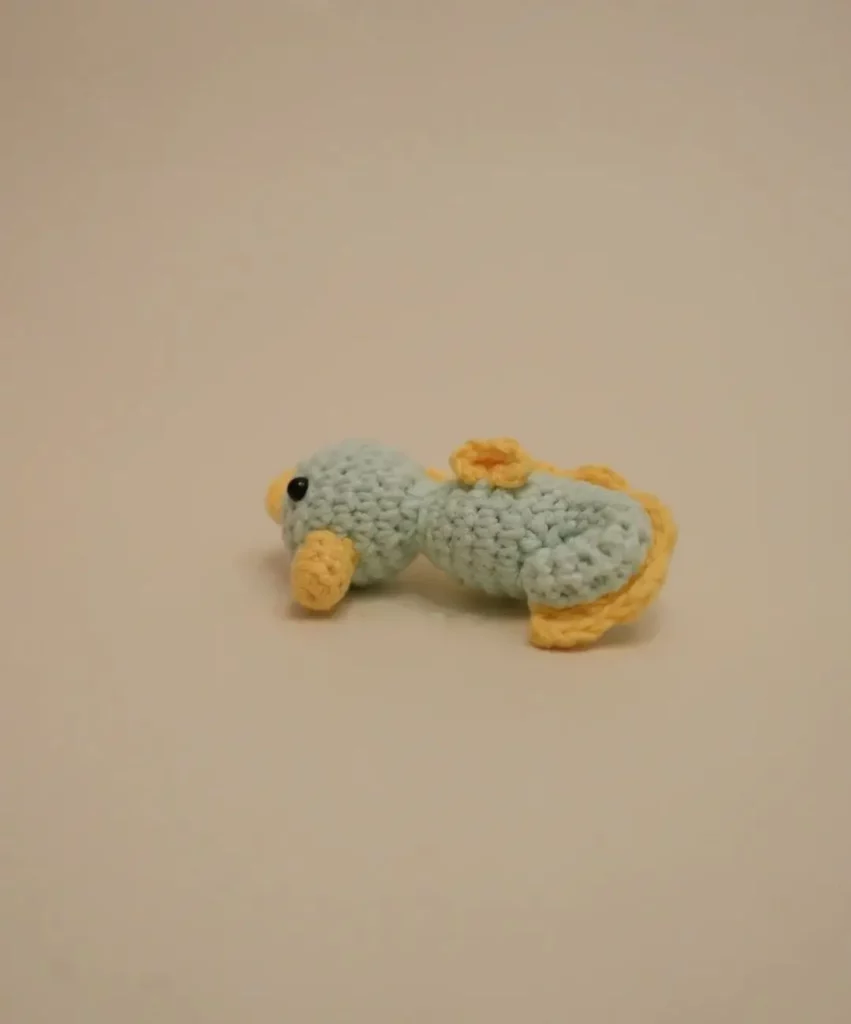 Light blue crocheted fish toy with yellow accents.