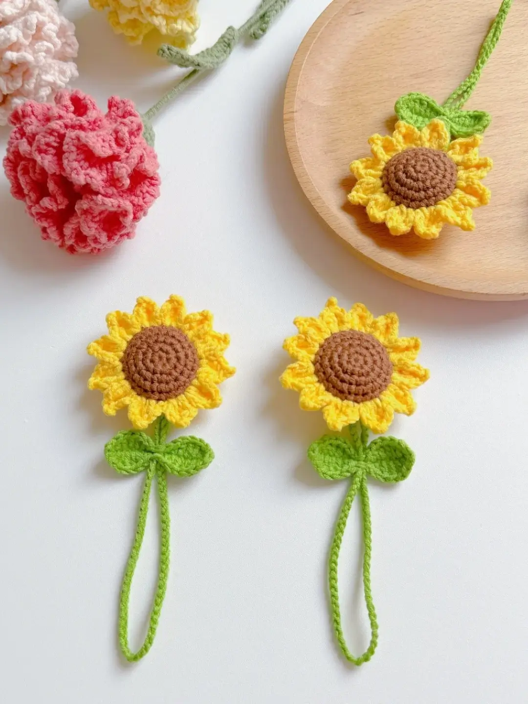 Two crocheted sunflowers with green leaves.