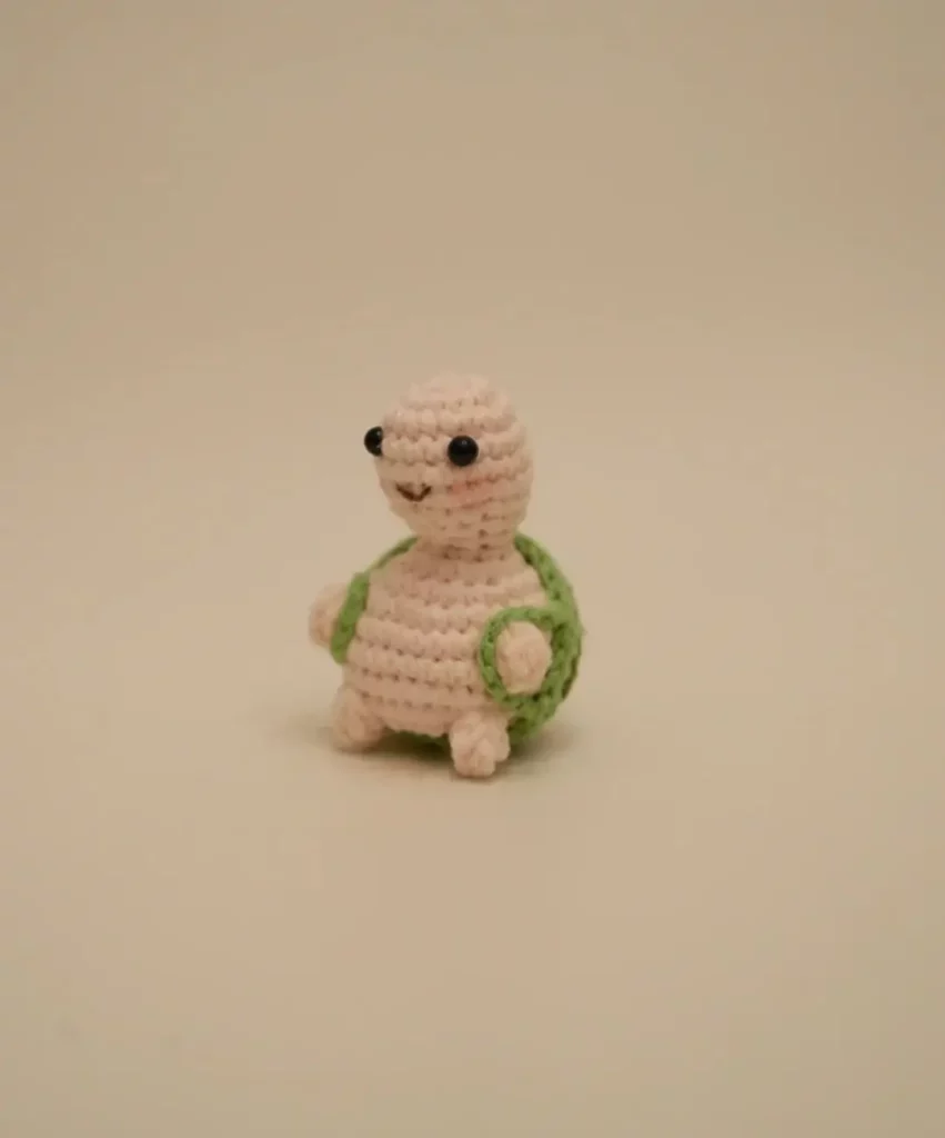 Crocheted turtle figurine, light pink shell, green shell detailing.