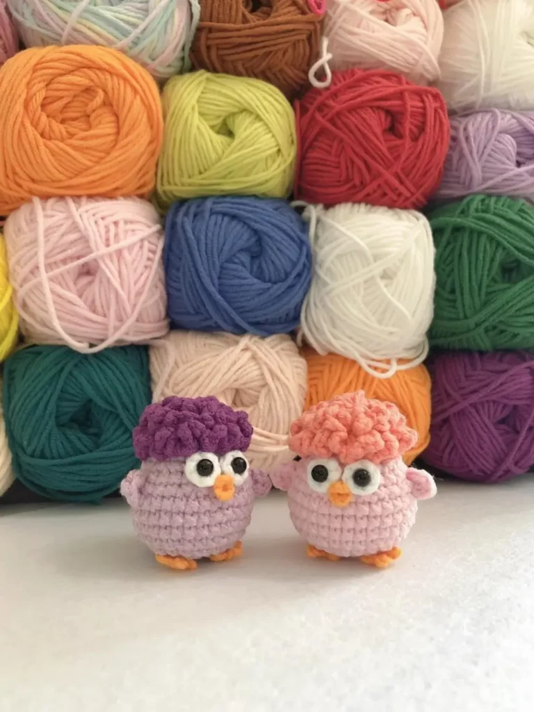 Two crocheted owl birds, pastel colors, yarn balls background.