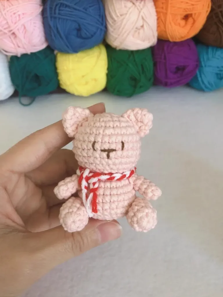 Crochet teddy bear, pink, red and white scarf.